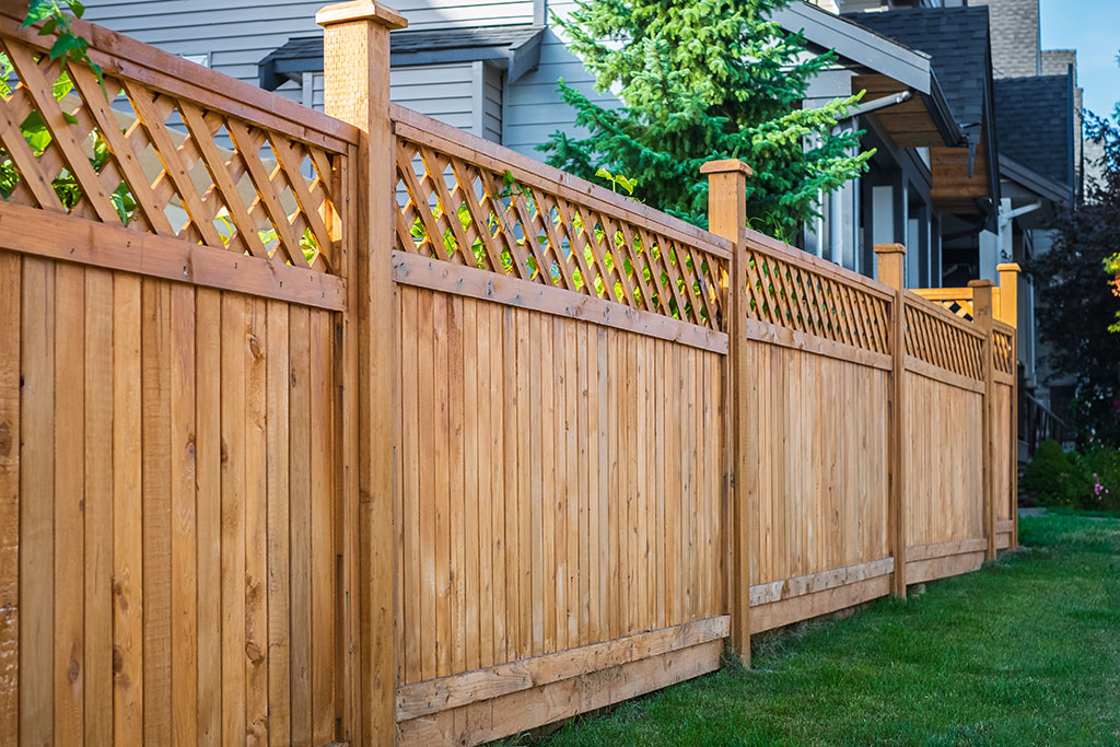 A Wooden Privacy Fence With a Lattice Top in Front of a House How to Build a Privacy Fence