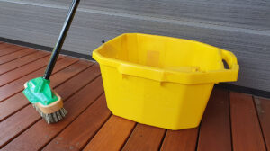 Closeup Of A Broom And A Yellow Bucket Sitting On A Wooden Deck Maintenance